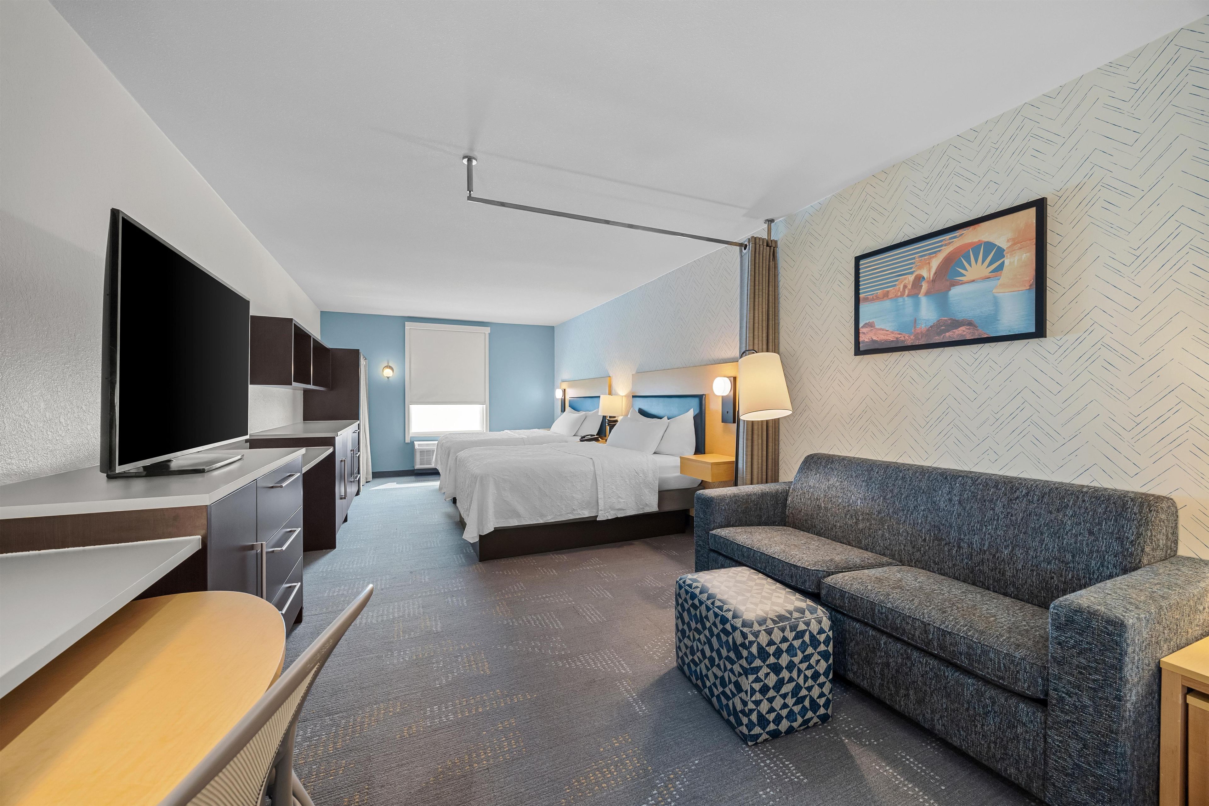 Una habitación de hotel con una cama, un sofá, un televisor y un escritorio.