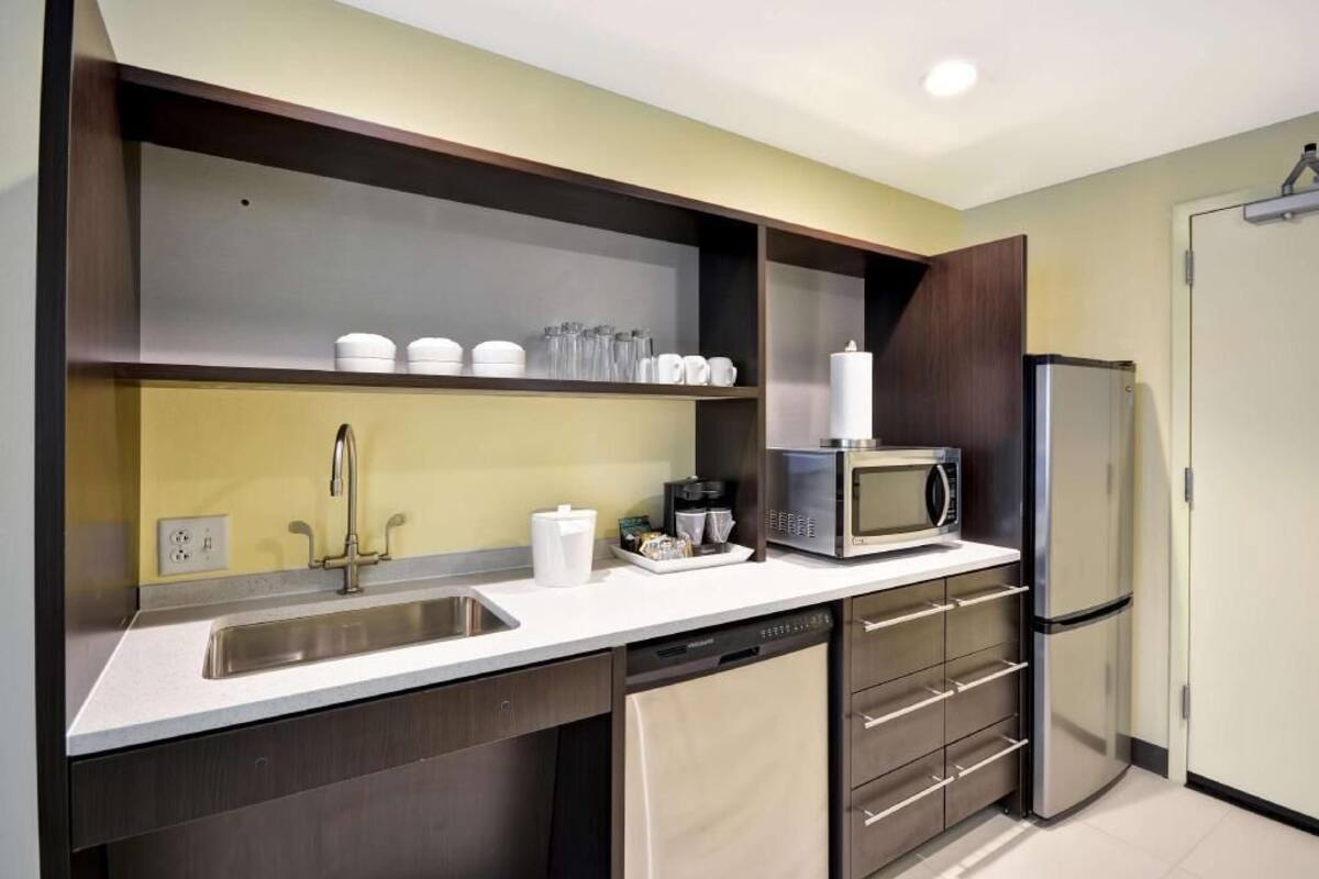 A modern kitchen with a stainless steel sink, a microwave, a refrigerator, and a dishwasher.
