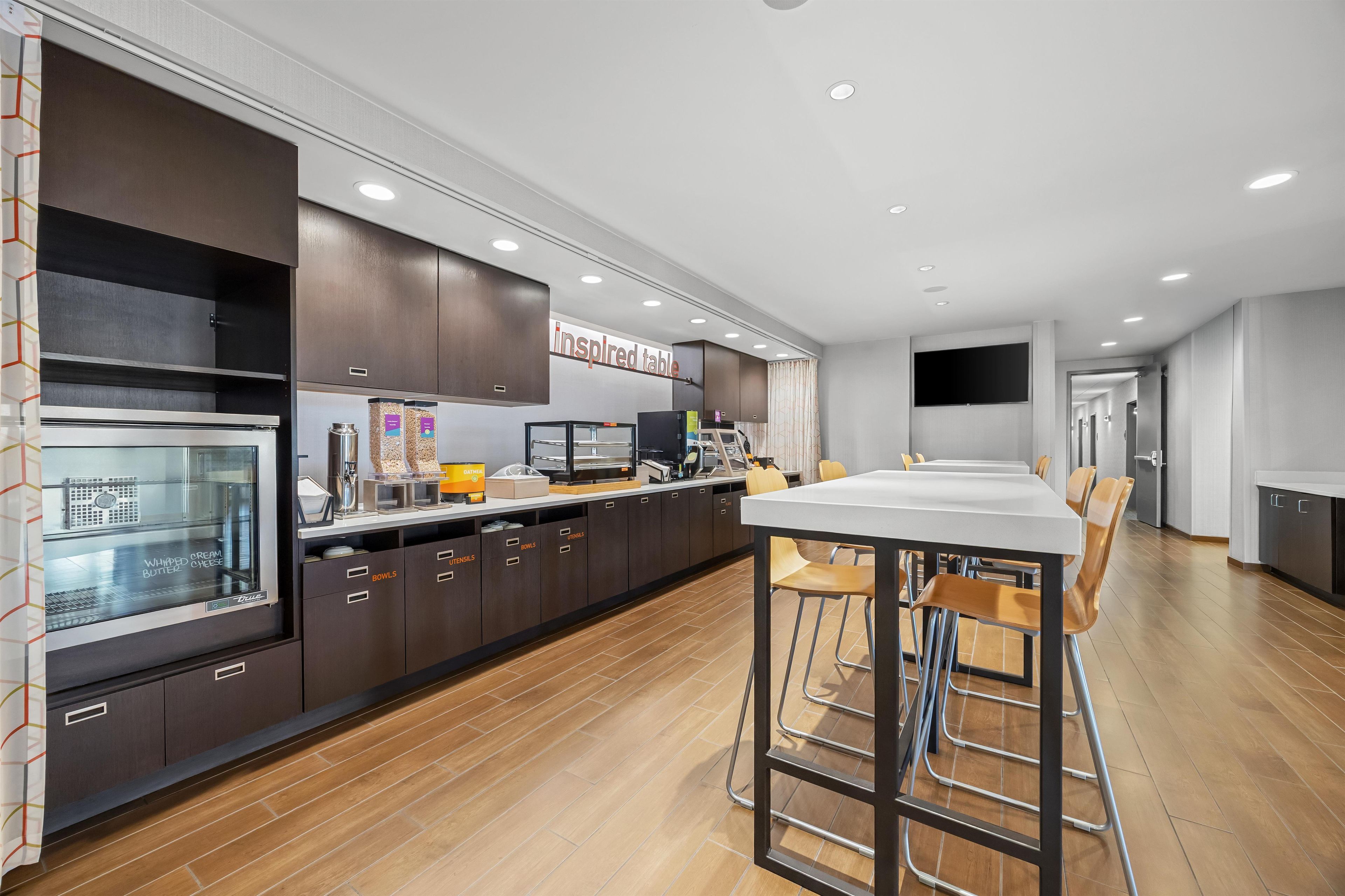 Una cocina moderna con una isla central, taburetes de bar y un televisor de pantalla plana montado en la pared.