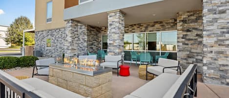 An outdoor seating area with a fire feature, stone walls, and modern furniture.