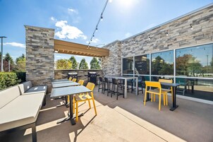 An outdoor patio with tables and chairs, stone walls, and a pergola.