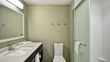 Une salle de bain avec deux lavabos, des toilettes et une douche à parois de verre.