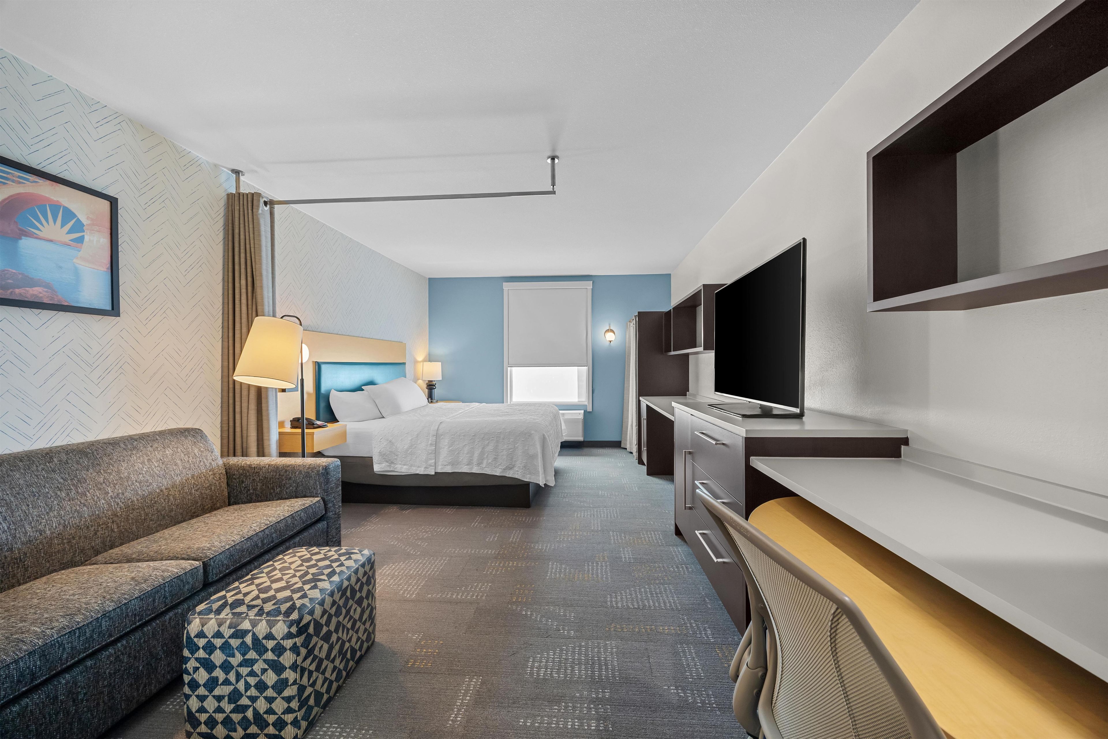 Una habitación de hotel con cama, sofá, escritorio y televisión.