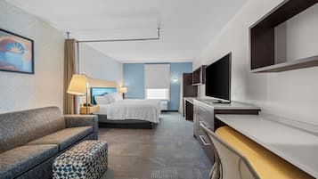 Una habitación de hotel con cama, sofá, escritorio y televisión.