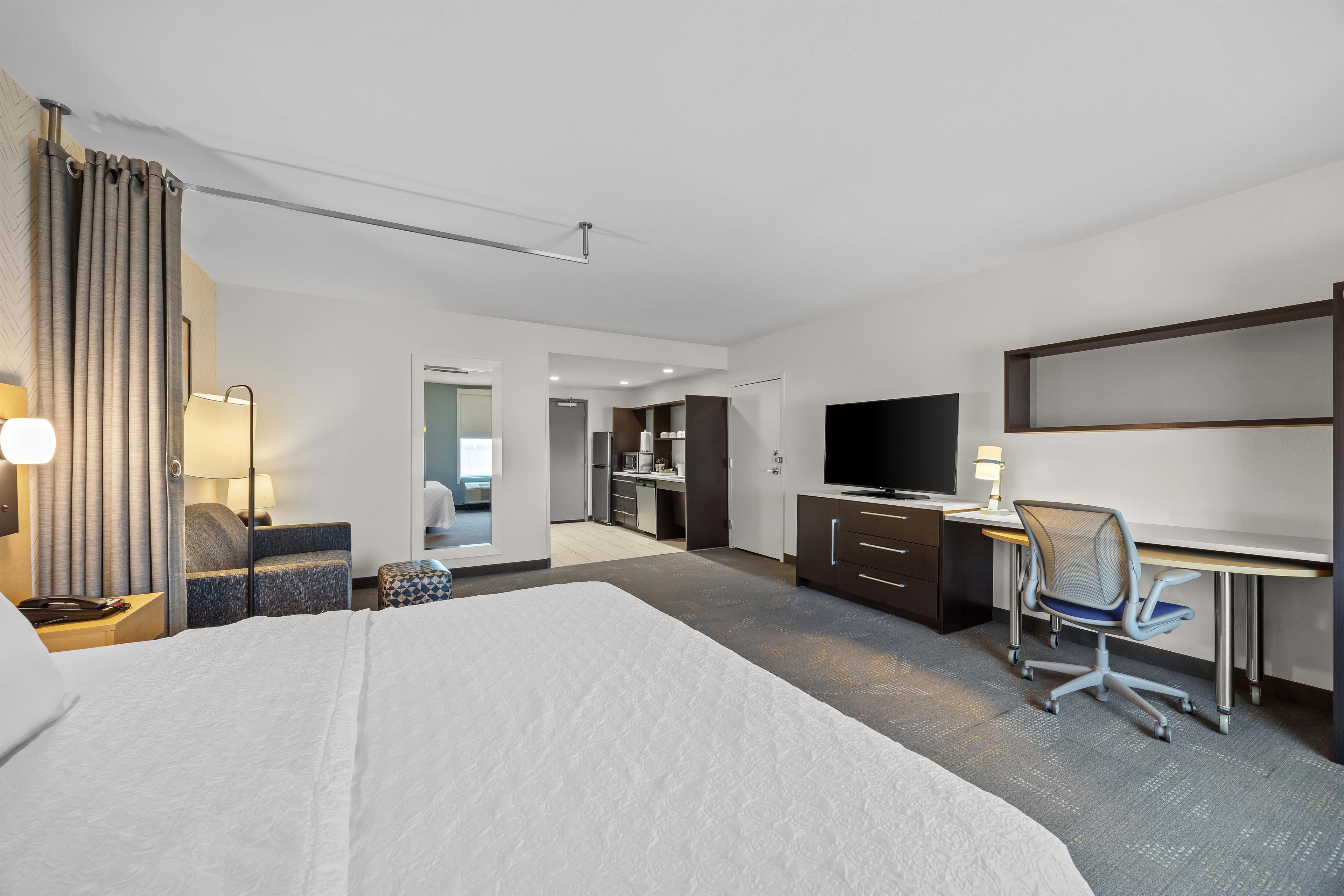 Une chambre d’hôtel équipée d’un lit, d’un bureau, d’une chaise, d’une télévision et d’une kitchenette.