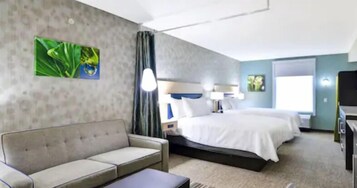 A hotel room with a bed, a sofa, a desk, and a window.