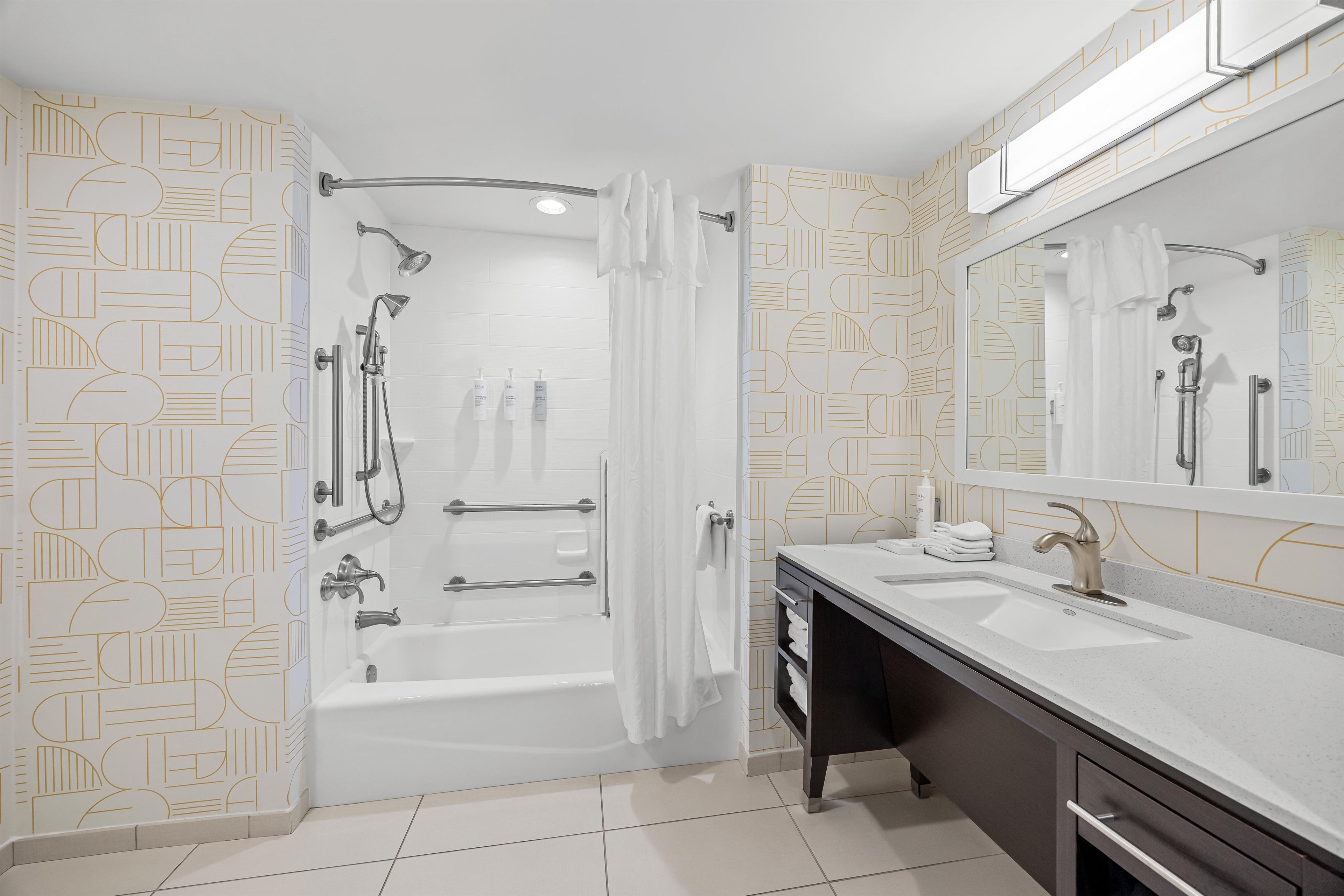 Un baño moderno con bañera, ducha y tocador con espejo.