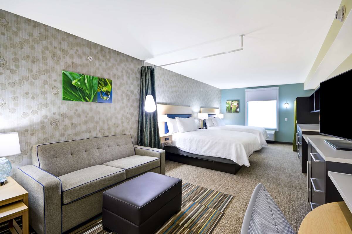 A hotel room with a sofa, a bed, a desk, and a television.