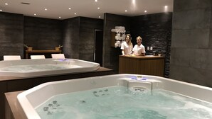 Un moderno espacio de spa con dos jacuzzis, asientos de madera y un mostrador de recepción.