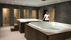 Un moderno cuarto de spa con dos tinas de hidromasaje grandes, paneles de madera y piso de baldosas.