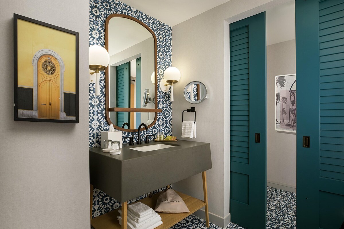 A bathroom with a large mirror, a sink, and a towel rack.