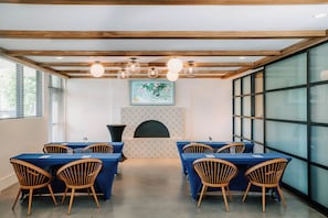 A conference room with wooden beams, a fireplace, and large windows.
