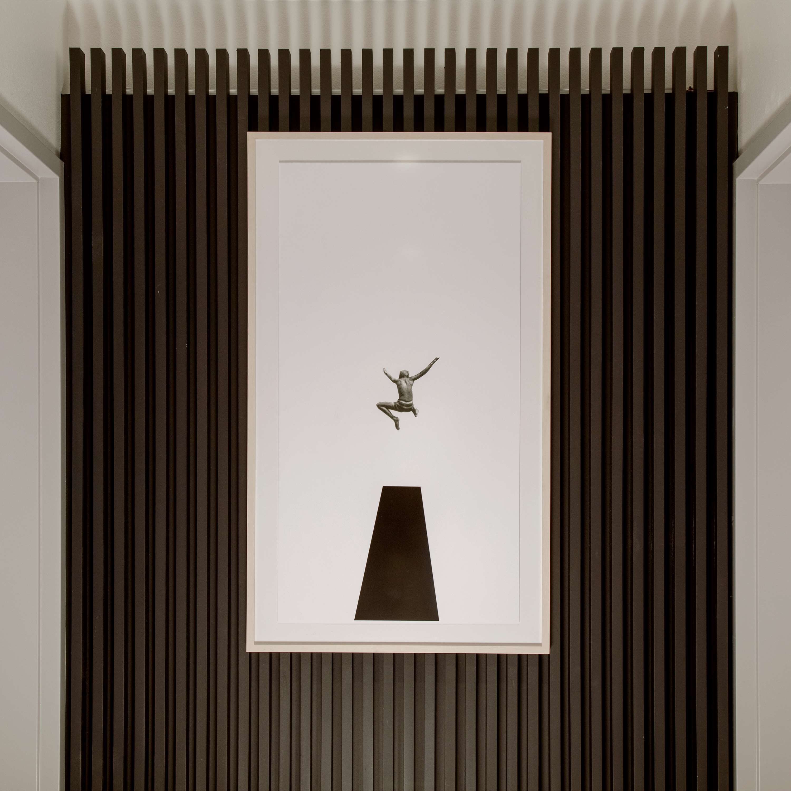 Una escultura enmarcada de un pájaro con alas extendidas sobre un muro con listones verticales.