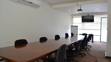 Una sala conferenze con un lungo tavolo in legno, sedie nere, una lavagna e un'ampia finestra.