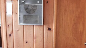 A room with a wooden wall, a black stove, and a white chair. - Chapel Hill Motel (Moran)