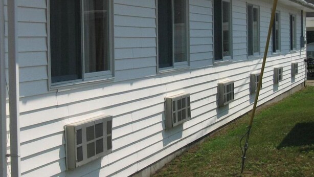 A single-story white building with multiple windows and vents. - Chapel Hill Motel (Moran)