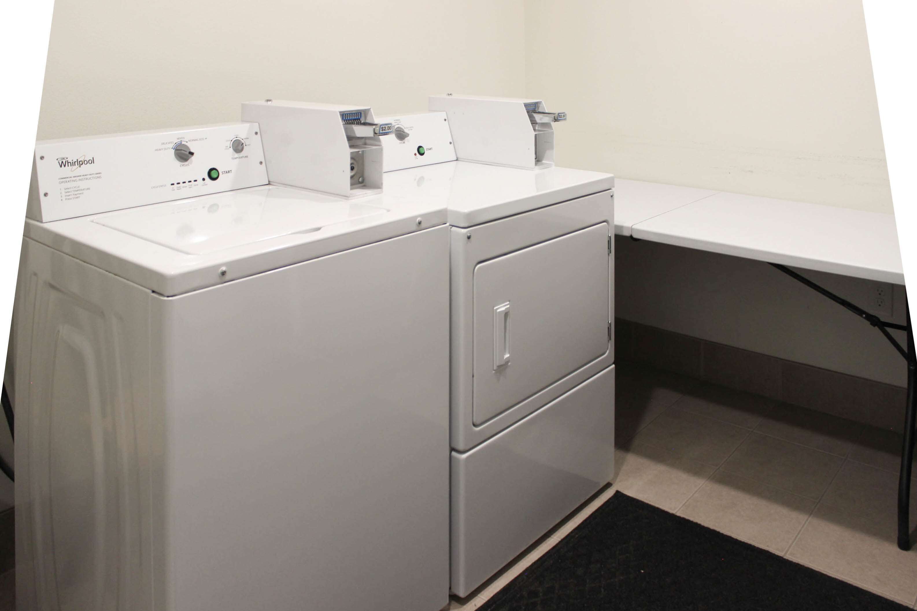 A compact, white Whirlpool washer and dryer unit with a control panel, located in a small laundry room with a tiled floor and a black rug.