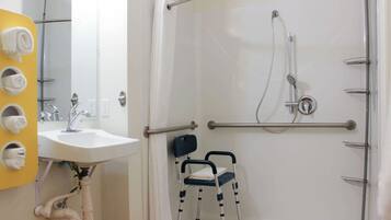 Un baño con ducha, lavamanos y silla de ruedas.