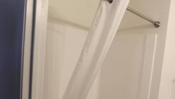 A bathroom with a white bathtub, a shower curtain, and a toilet.
