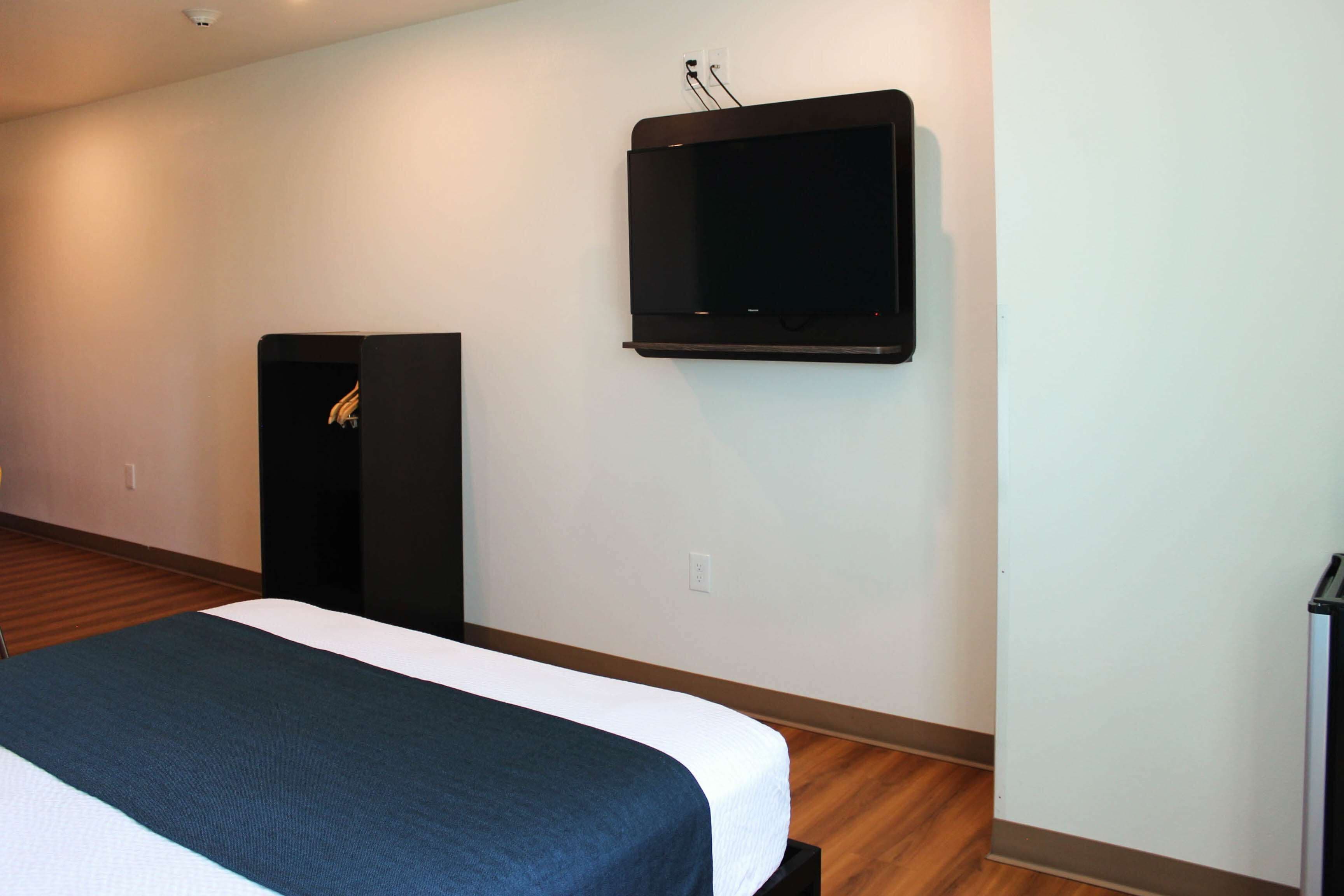 A hotel room with a bed, a television mounted on the wall, and a speaker.
