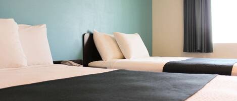 A hotel room with two beds, a nightstand, and a window with curtains.