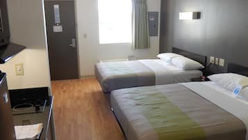Habitación de hotel con dos camas, kitchenette, ventana con cortinas y una lámpara fijada a la pared.