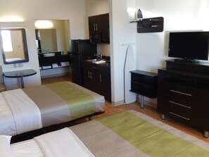 A hotel room with two beds, a small table, a TV, a microwave, and a sink. - Studio 6 Yukon, OK (Yukon)