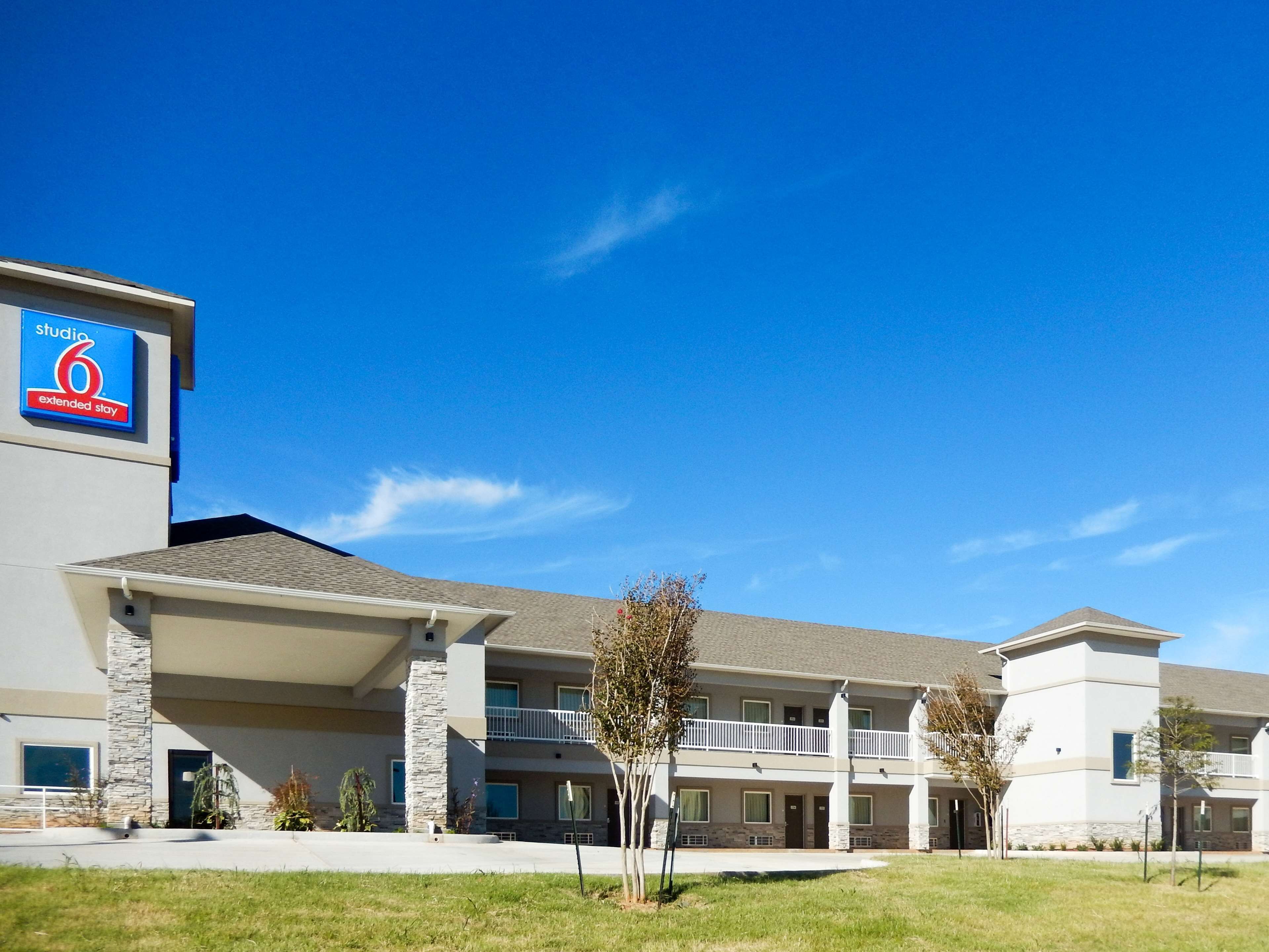 A modern hotel with a two-story structure, a covered entrance, and a sign for 'Studio 6 Extended Stay'.