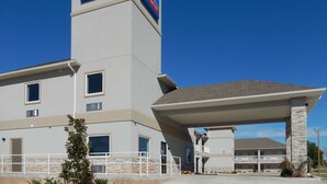 A modern hotel with a prominent '6 extended stay' sign, a covered outdoor area, and a stone facade. - Studio 6 Yukon, OK (Yukon)