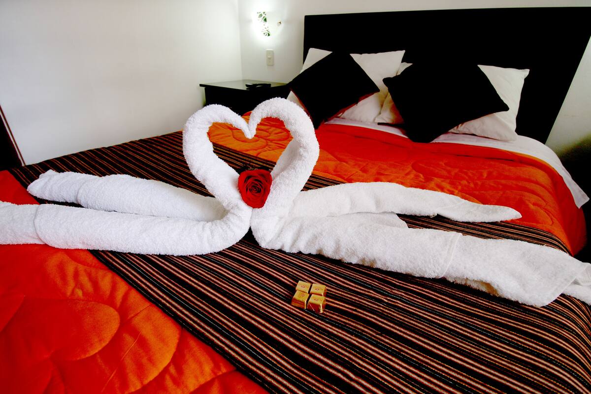 Ein Bett mit einer herzförmigen Handtuchanordnung und einer einzelnen Rose.