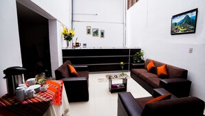 A modern living room with a sofa set, a coffee table, and a dining table with dishes. - Hotel Peru Real (Cusco)