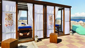 A seaside room with a bed, a small table, and a view of the sea.