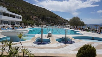 Una piscina techada, una piscina al aire libre, sombrillas