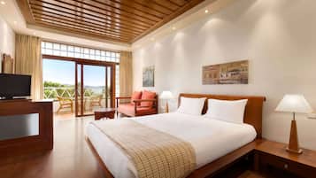 Een hotelkamer met een groot bed, een televisie, een bureau en een balkon met uitzicht.