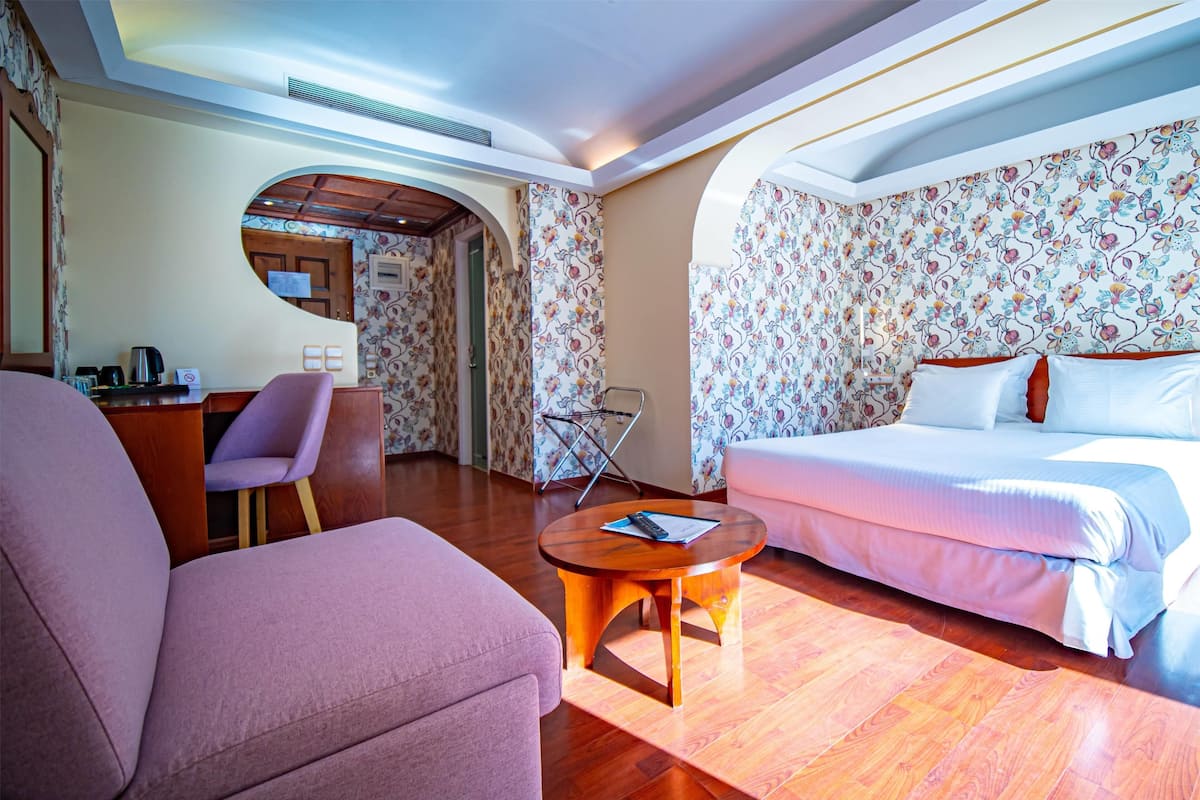 Ein Hotelzimmer mit einem Bett, einem Sofa, einem Schreibtisch mit Stuhl und einem kleinen runden Tisch.