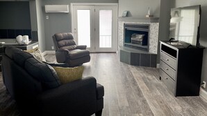 Una sala moderna con un sofá de cuero oscuro, un sillón reclinable y una chimenea.