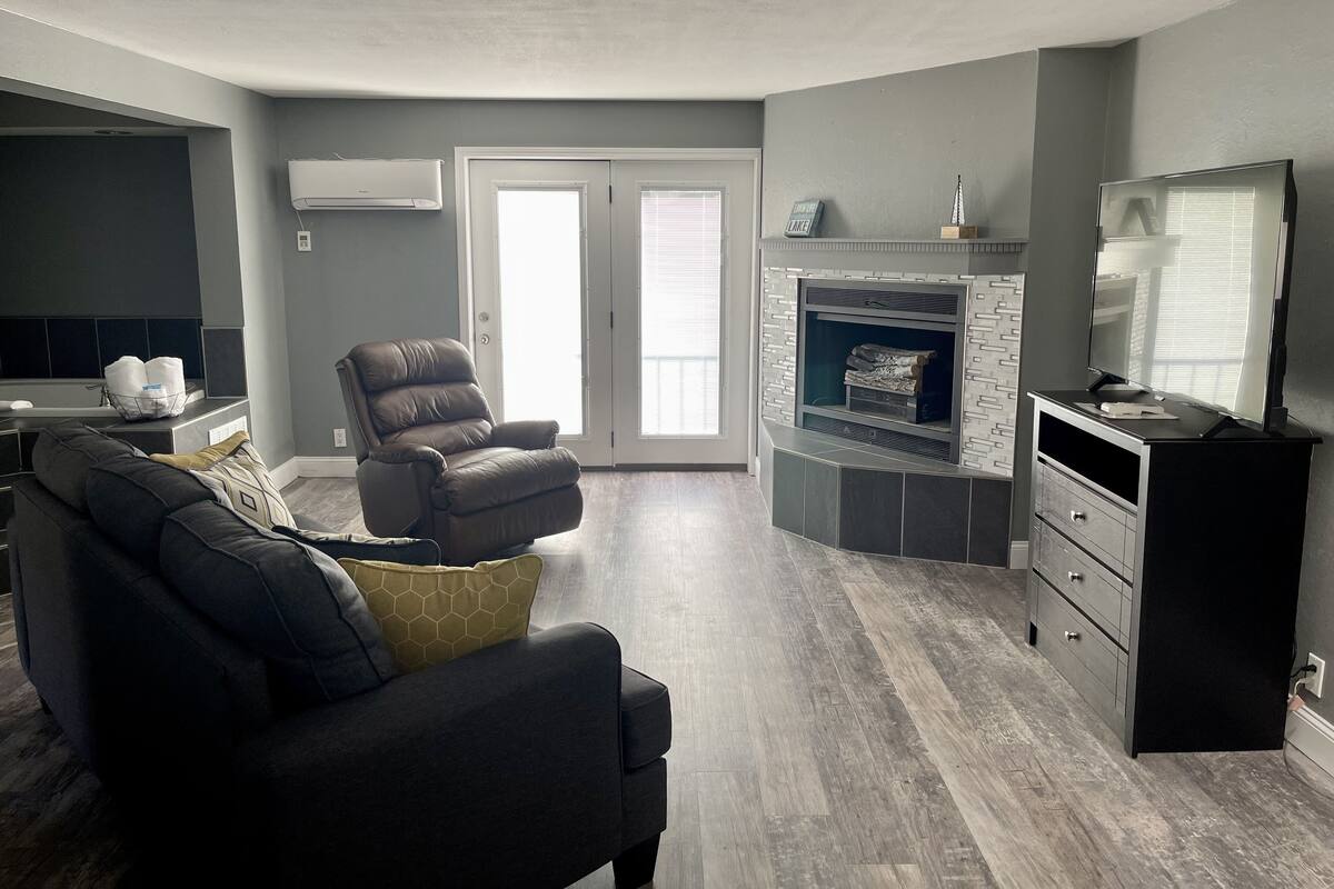 A modern living room with a dark leather sofa, a recliner, and a fireplace.