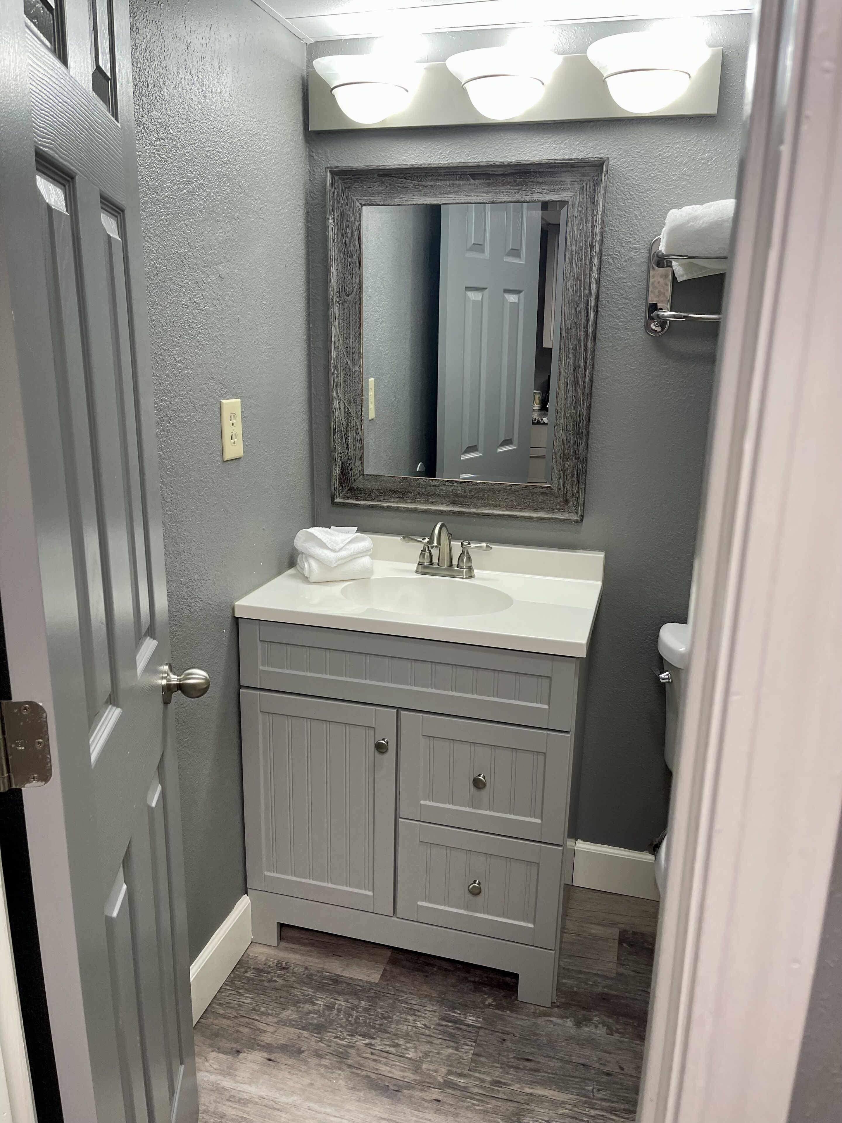 A bathroom with a gray vanity, a mirror, and a toilet.