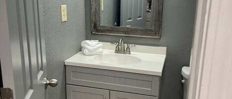 A bathroom with a gray vanity, a mirror, and a toilet.