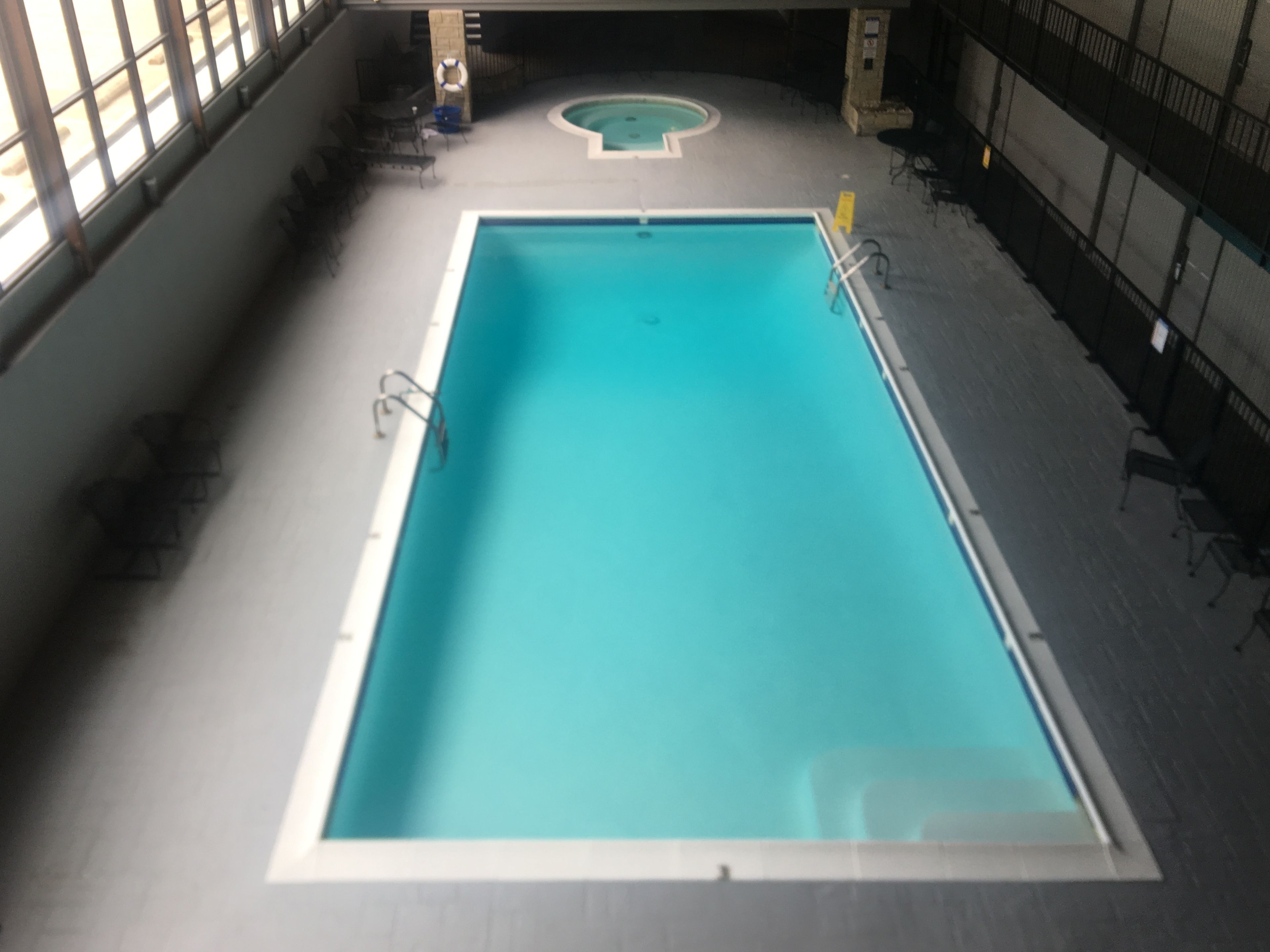 An indoor swimming pool with a rectangular shape and a smaller circular pool in the background.