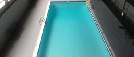 An indoor swimming pool with a rectangular shape and a smaller circular pool in the background.