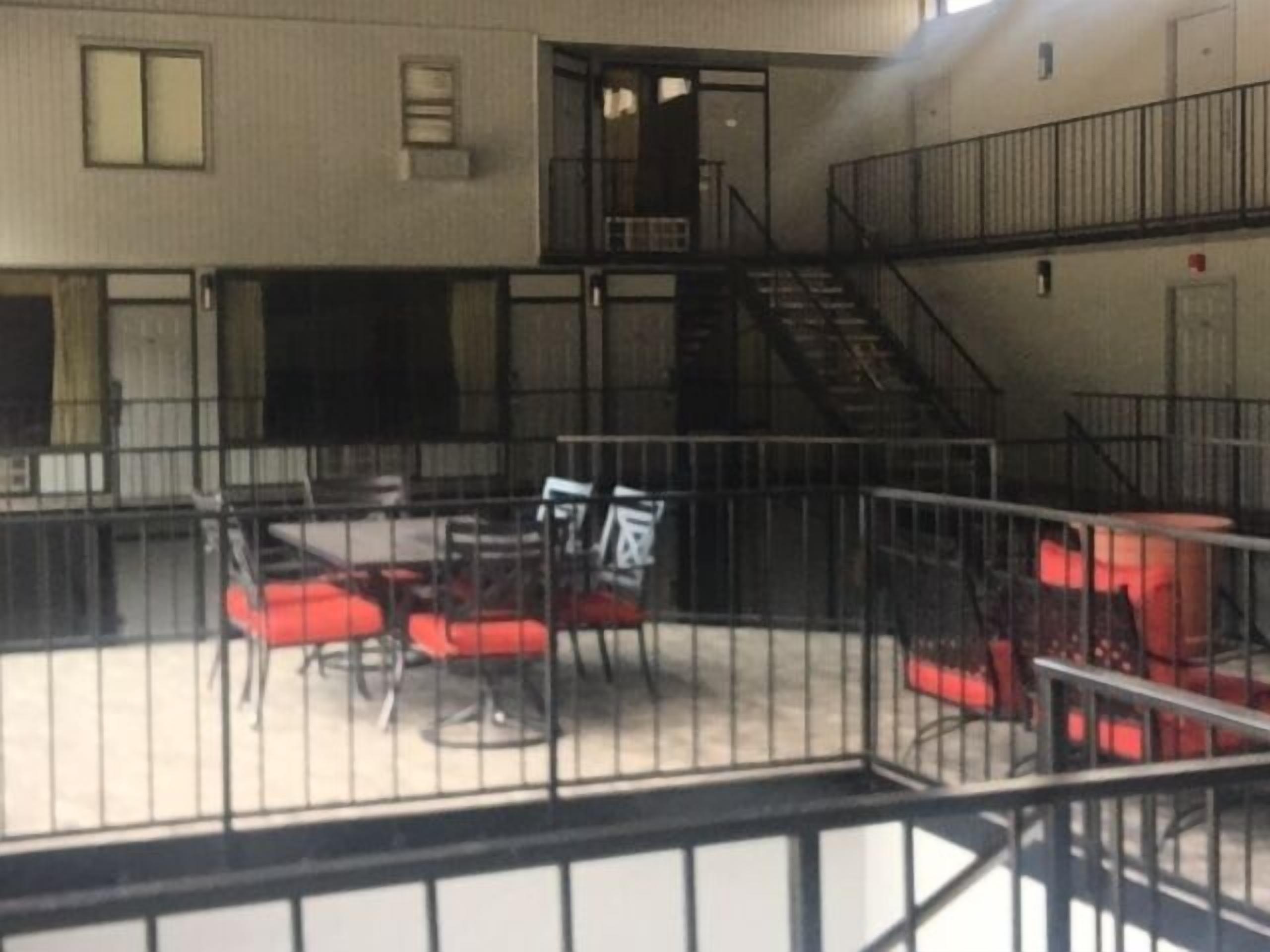 A multi-level indoor space with a staircase, metal railings, and a seating area with red chairs.
