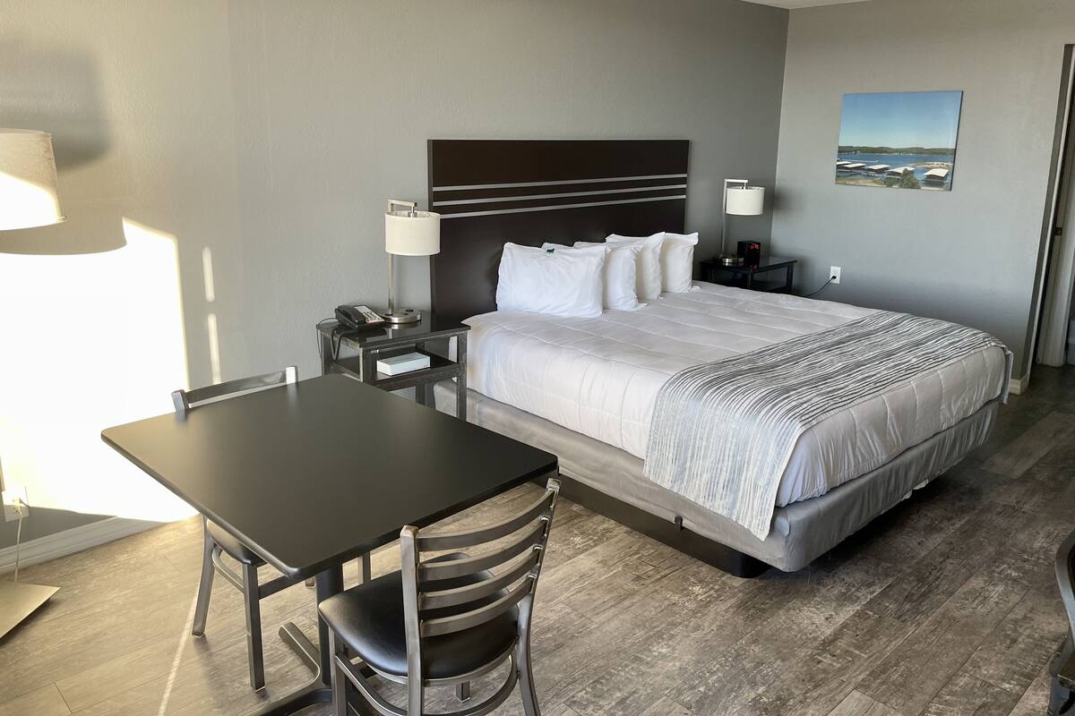 A hotel room with a bed, bedside tables, a desk, and chairs.