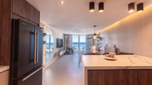 Cozinha moderna com uma ilha grande, frigorífico encastrado e vista para o mar.