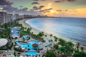 A resort with a large swimming pool, beach access, and high-rise buildings in the background.