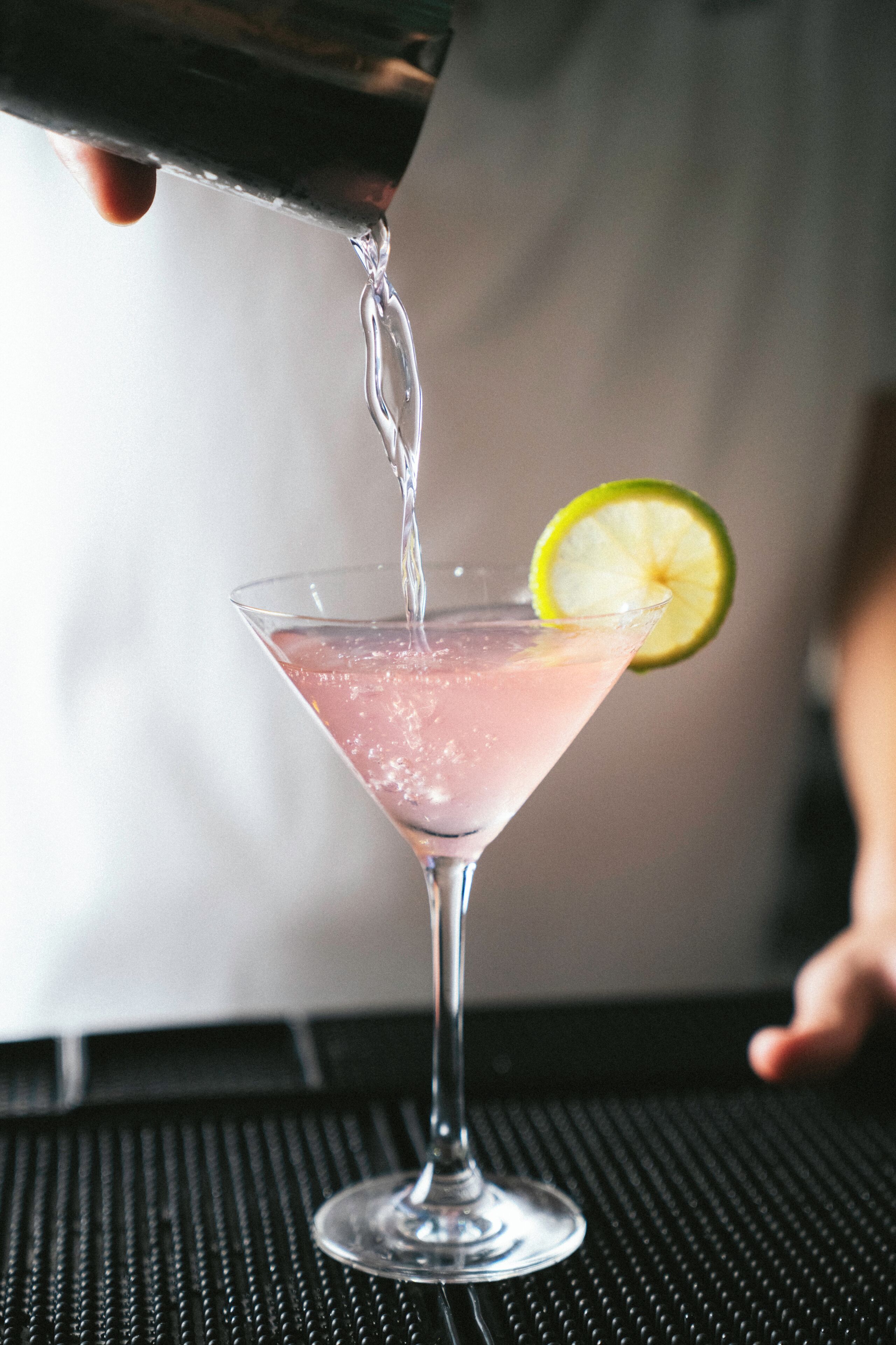 Ein Martini-Glas mit Limettenscheibe auf einer schwarzen, strukturierten Oberfläche.