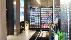 Entrada de un hotel con una recepción, una pantalla digital y un mostrador de llaves de coche.