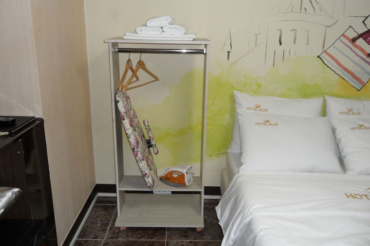 Habitació d'hotel amb un llit, un armari i una paret amb un mural.