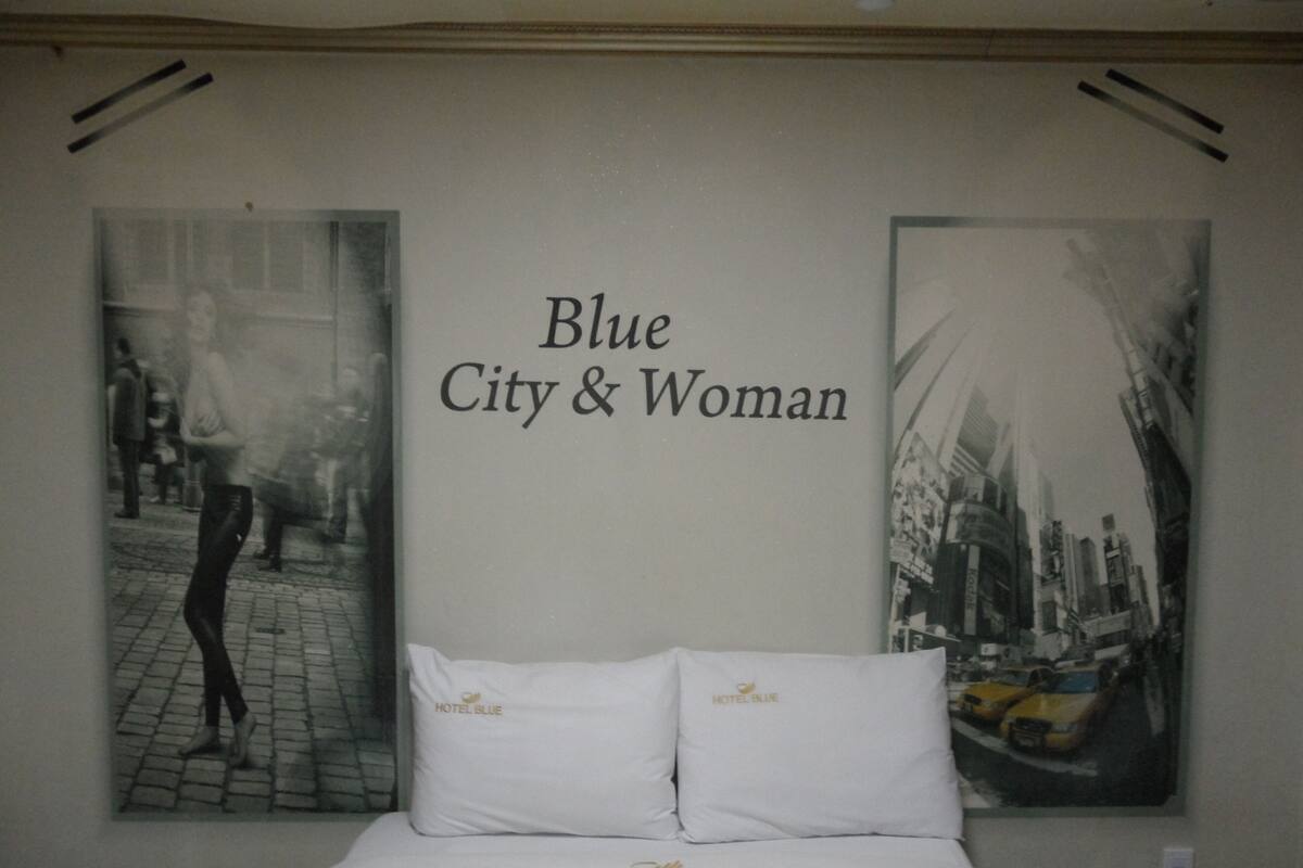 A bedroom with a bed, pillows, and two posters on the wall.