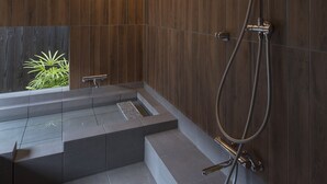 A modern bathroom with a wooden wall, a built-in shower, and a small window with plants. - Sanjusangendo Yoitsubaki (Kyoto)